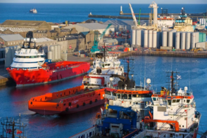 image shows Aberdeen Harbour in full sunlight with fishing vessels in sight of the quay and harbour wall